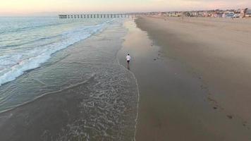 Luftaufnahme eines jungen Mannes, der am Strand läuft.