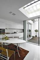 Modern oval dining table overlooking the white kitchen and courtyard photo