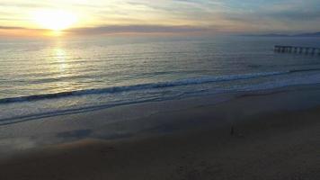 ripresa aerea del sole che tramonta su un orizzonte di spiaggia e oceano. video