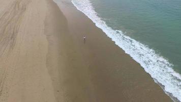 luchtfoto van een jonge man die op het strand loopt.