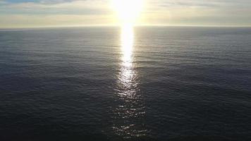 Luftaufnahme der untergehenden Sonne über einem Strand- und Ozeanhorizont.