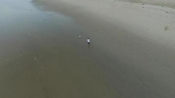 foto aérea de menino jogando futebol na praia ao pôr do sol. video