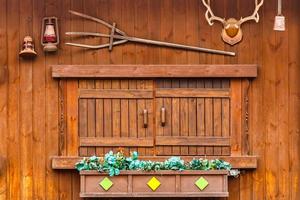 Ventana de madera en casa de madera y decorada con campana de lámpara de asta de planta y tridente foto