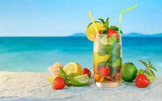 Mojito cocktail. White rum cocktail with fresh ingredients. Cold ice drink on blurred beach background.