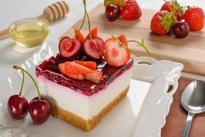 tarta de queso con frutos rojos, fresas frescas y tarta de queso cereza en la mesa. foto