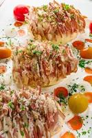 Potato filled with bacon ready to be baked in oven. Sour cream for cooking with carrot, tomato, onion, spices and herbs in baking dish. photo