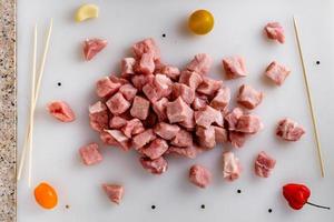 Raw meat, sliced pork steaks on kitchen  table. Meat processing. Skewers preparation. photo