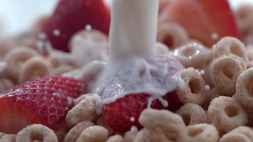 Primer plano de leche vertida en un tazón de cereal con fresas filmada en phantom flex 4k a 1000 fps video