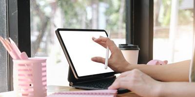 Cerrar la mano de la mujer con lápiz óptico escribiendo en el bloc de notas digital, tocando en la pantalla de la tableta digital trabajando en una computadora portátil en la oficina, diseñador web trabajando en un proyecto foto