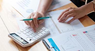 Close up businesswoman using calculator and laptop for doing math finance on wooden desk in office and business working background, tax, accounting, statistics, and analytic research concept photo