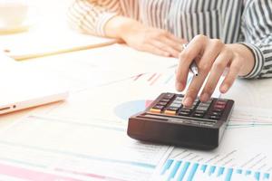 empresaria usando una calculadora y escribiendo notas. impuestos, ahorros, finanzas y concepto de economía foto