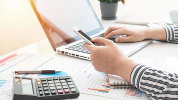 empresaria usando una calculadora y escribiendo notas. impuestos, ahorros, finanzas y concepto de economía foto