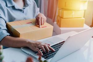 Closeup view of female's online store, small business owner seller, entrepreneur packing package, post shipping box preparing delivery parcel on the table, entrepreneurial self-employed business concept