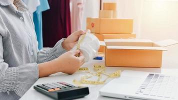 Vista de cerca de la tienda en línea de la mujer, vendedor propietario de una pequeña empresa, paquete de embalaje del empresario, caja de envío postal que prepara el paquete de entrega sobre la mesa, concepto de negocio autónomo empresarial foto