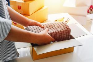 Closeup view of female's online store, small business owner seller, entrepreneur packing package, post shipping box preparing delivery parcel on the table, entrepreneurial self-employed business concept photo