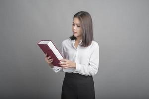 Hermosa mujer maestra sosteniendo un libro sobre fondo gris foto