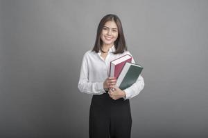 Hermosa mujer maestra sosteniendo un libro sobre fondo gris