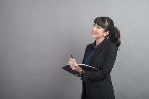 Hermosa mujer de negocios escribiendo algo sobre fondo gris foto