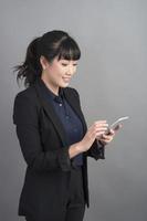 Beautiful business Woman using smartphone on grey background photo