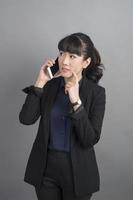 Beautiful business Woman using smartphone on grey background photo