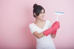 Hermosa ama de casa asiática sonriendo sobre fondo rosa foto