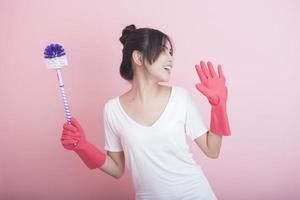 Hermosa ama de casa asiática sonriendo sobre fondo rosa foto