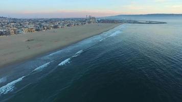 ripresa aerea di una città panoramica sulla spiaggia e sull'oceano al tramonto.