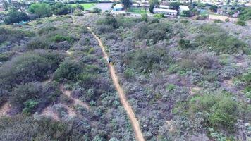 Aerial shot of a young man trail running on a scenic hiking trail.