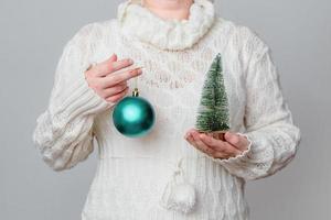 Woman holds a Christmas tree and an ornament photo