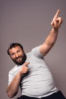 Happy handsome bearded excited man in gray t-shirt with hands up celebrating photo