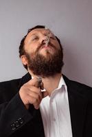 Bearded man in modern coat and shirt smoking his cigar photo