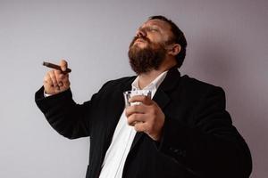 Bearded man in modern coat and shirt smoking his cigar photo