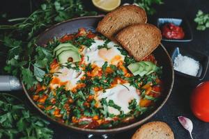 Shakshuka with eggs, tomatoes, bell pepper and parsley in a pan. Shakshuka is a traditional Israeli food. photo