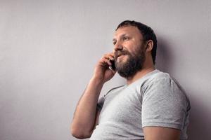 hombre barbudo en camiseta gris con teléfono móvil