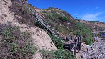 antennskott av en ung man som kör trappor på sidan av en klippa vid havet. video