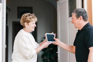 Women greeting men at doorway with electronic gadget purchase with online order photo