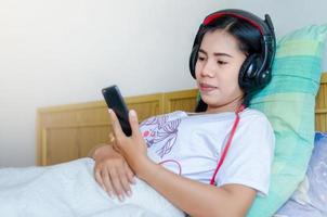 mujer durmiendo escuchando auriculares. chica asiática durmiendo en el sofá escuchando auriculares. foto