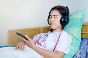 mujer durmiendo escuchando auriculares. chica asiática durmiendo en el sofá escuchando auriculares. foto