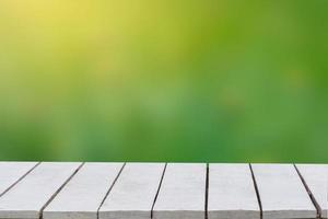 fondo verde natural con enfoque selectivo. el fondo verde tiene una hoja de bokeh y pasto sobre un piso de madera blanca. mesa vacía espacio vacío mesa de madera vacía foto