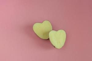 Heart shaped potatoes cut in half on a pink background. Concept of farming, harvesting, vegetarianism photo