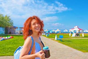 mujer pelirroja, en, vestido, bebidas, en, playa, con, pasto verde foto