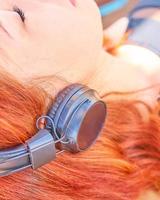 Beautiful woman in swimwear listening to music on the beach photo