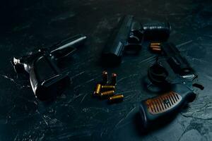 Three guns and bullets on black table.