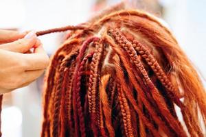 Cerca del proceso de trenzado de trenzas africanas con kanekalon de colores. foto