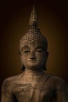 estatua de buda utilizada como amuletos de la religión del budismo. el antiguo buda, fondo marrón oscuro. foto