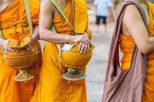 las limosnas en torno a las túnicas amarillas de los monjes caminan sobre las limosnas como una actividad budista. foto
