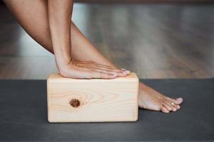 Extended triangle pose with brick closeup, utthita trikonasana pose using wooden block in yoga iyengar in studio photo