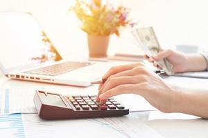 Businesswoman using a calculator and writing notes. Taxes, savings, finances, and economy concept photo