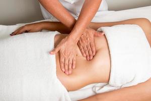 terapeuta de masaje masajeando el estómago de una mujer foto