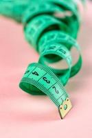 Measure Tape. Body measuring curly ruler sewing cloth Tailor soft tape on pink rose background. photo